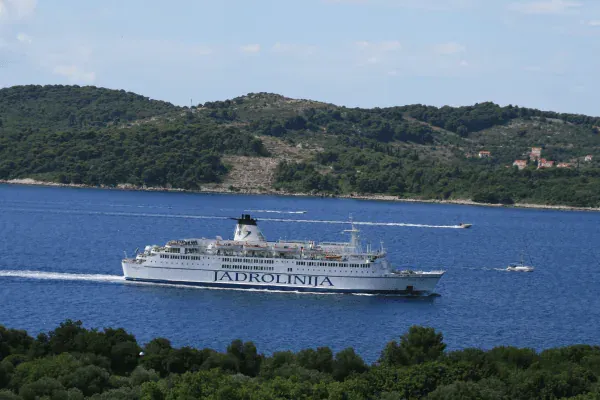 A Jadrolinija car ferry passing a wooded island on the Croatian coast