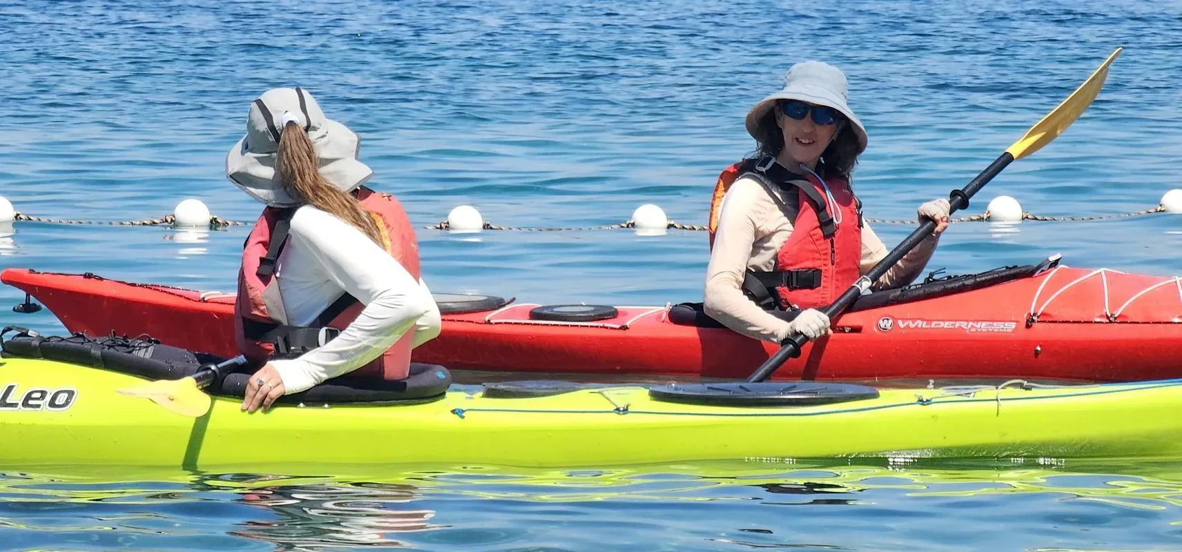 Two kayakers side by side in a tandem sea kayak on calm water