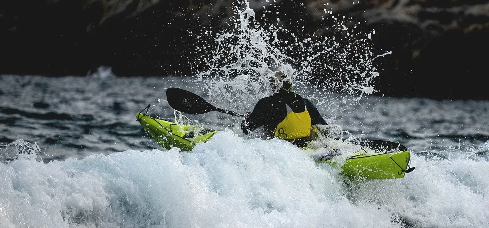 A kayaker punching through breaking surf during a kayak course