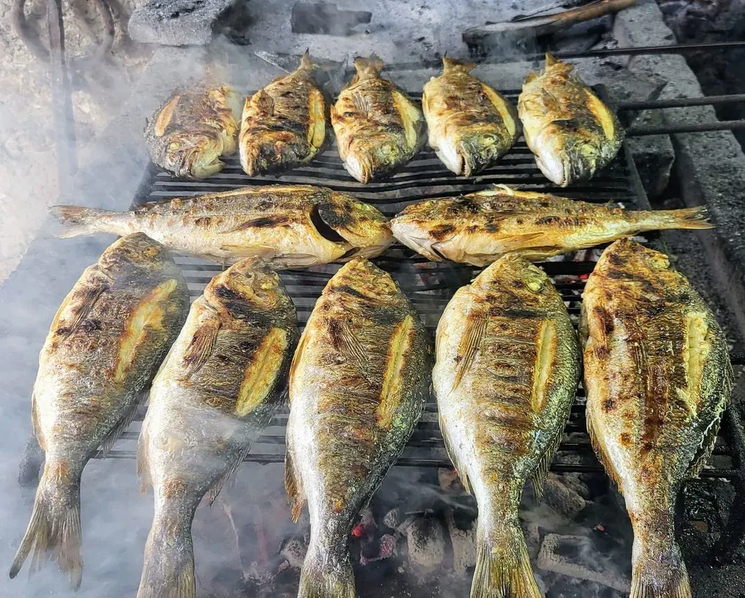 Whole fish grilling over charcoal