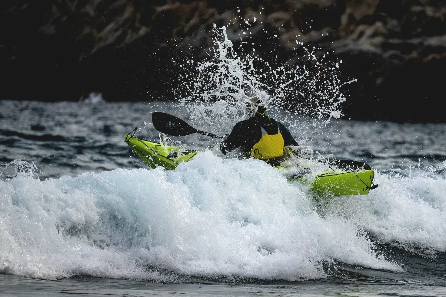 Kayaker punching through a breaking wave during a kayak course