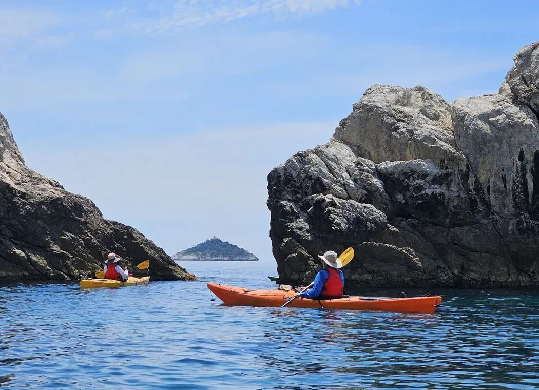 Kayakers paddling between rock outcrops toward an open islet