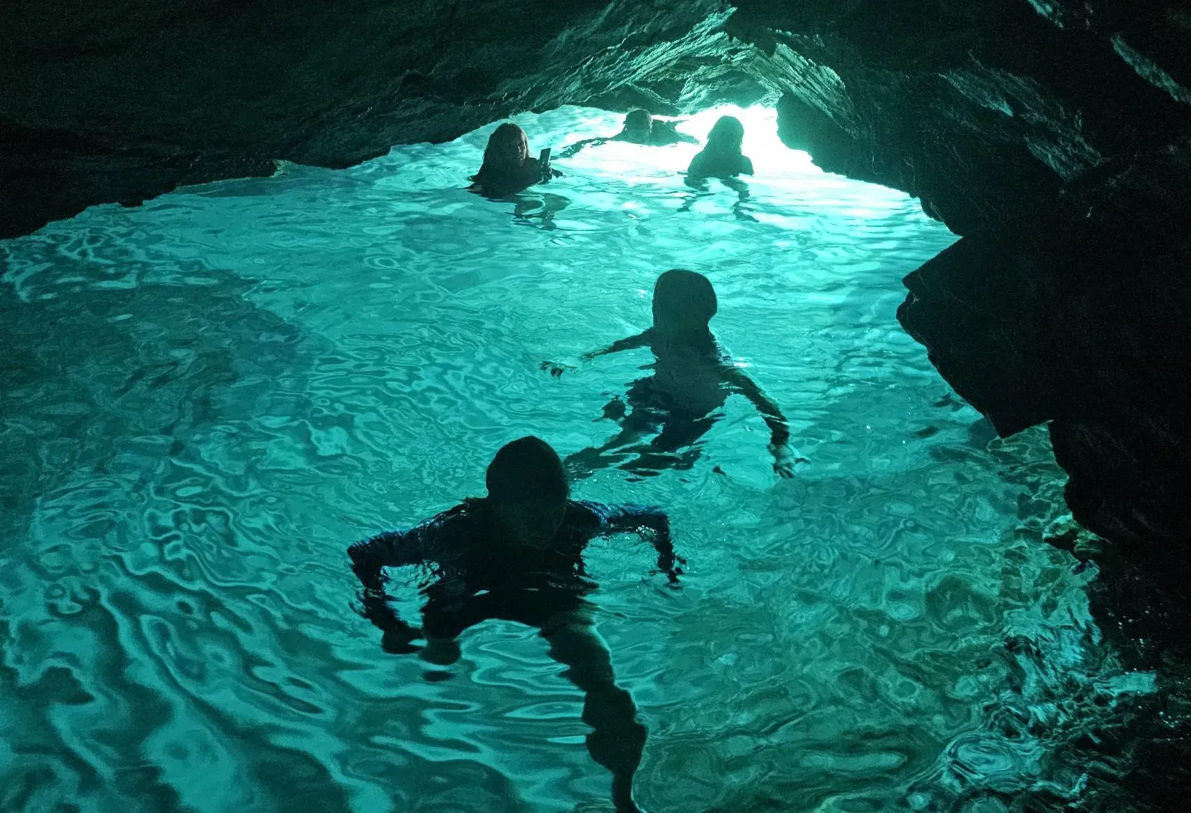 Swimmers in the turquoise light of a sea cave